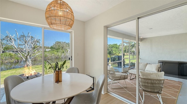 dining area featuring a wealth of natural light, a notable chandelier, a textured ceiling, and wood finished floors