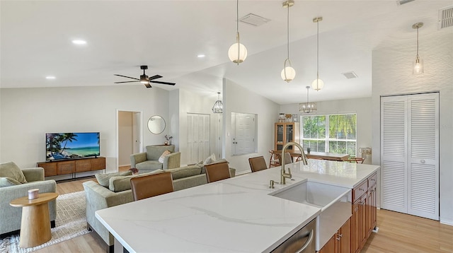 kitchen with a sink, visible vents, light wood-style floors, open floor plan, and vaulted ceiling