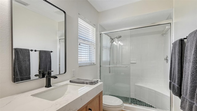 bathroom with visible vents, vanity, a shower stall, and toilet