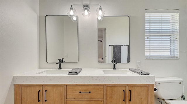 bathroom featuring a sink, toilet, and double vanity