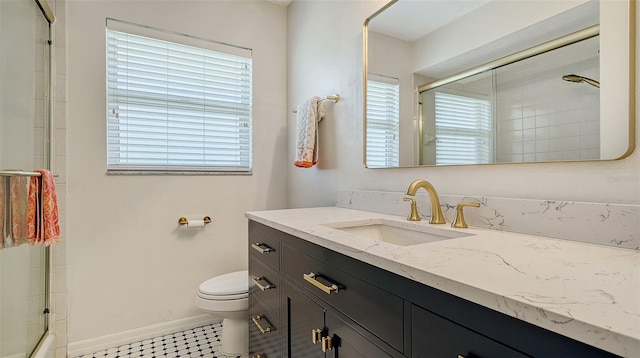 bathroom with baseboards, a shower with shower door, vanity, and toilet