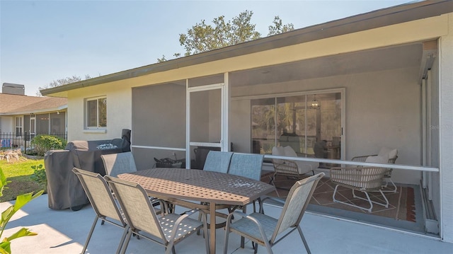 view of patio with outdoor dining space, a sunroom, and fence