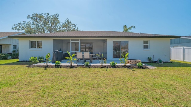 rear view of house with fence, a sunroom, a lawn, stucco siding, and a patio area