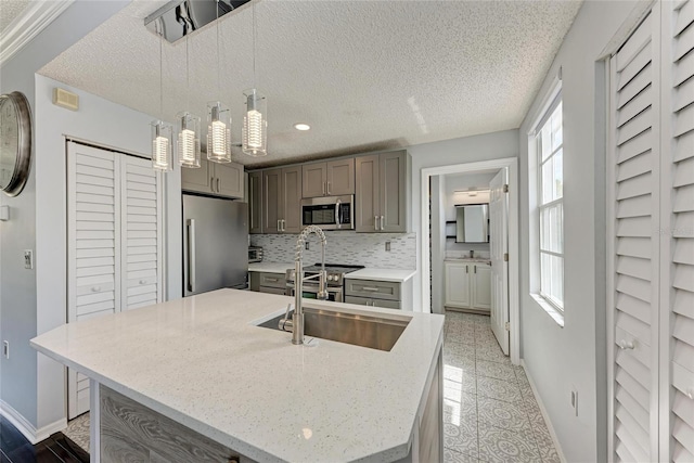 kitchen featuring appliances with stainless steel finishes, gray cabinets, a sink, and baseboards