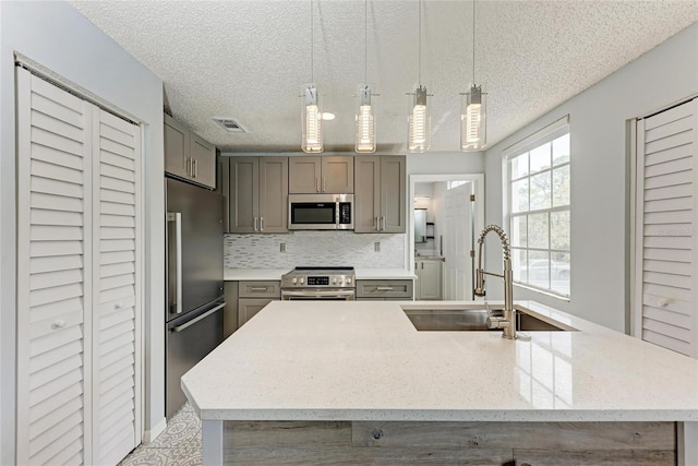 kitchen featuring stainless steel appliances, gray cabinets, visible vents, and a sink