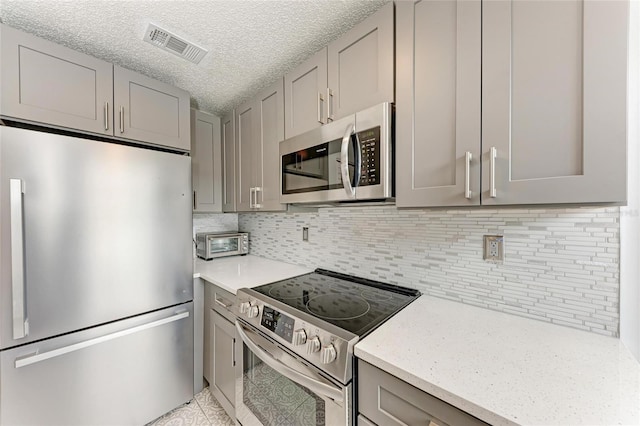 kitchen with a toaster, visible vents, appliances with stainless steel finishes, and gray cabinetry