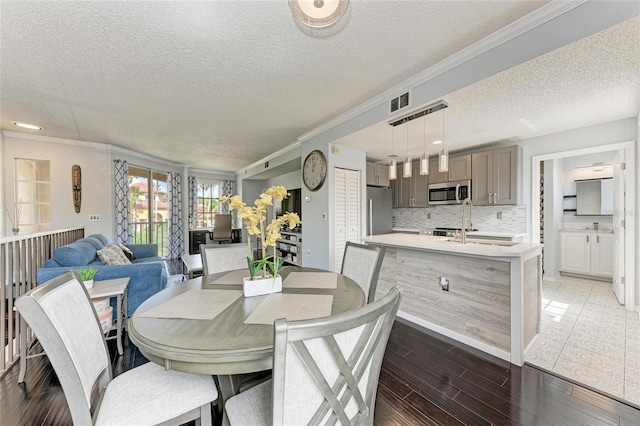 dining room with ornamental molding, visible vents, a textured ceiling, and wood finished floors