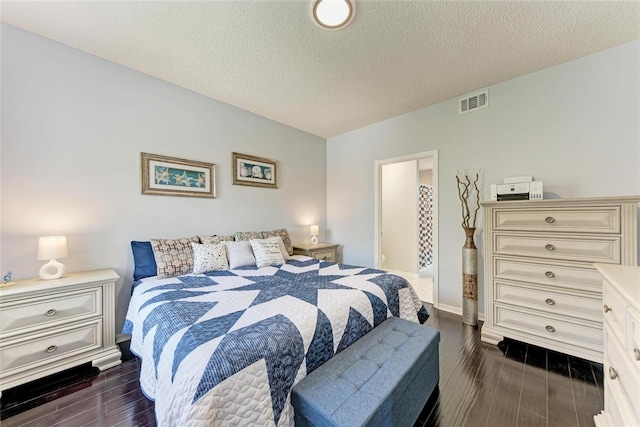 bedroom featuring wood tiled floor, visible vents, and a textured ceiling