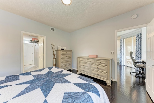 bedroom with dark wood-style floors, a textured ceiling, visible vents, and baseboards