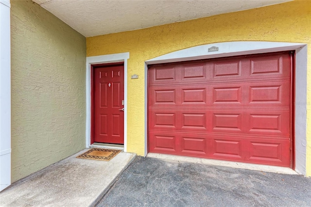 doorway to property with a garage and stucco siding