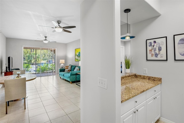 interior space featuring light stone countertops, open floor plan, pendant lighting, light tile patterned floors, and white cabinetry