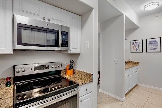 kitchen featuring light tile patterned floors, white cabinets, stainless steel appliances, and baseboards