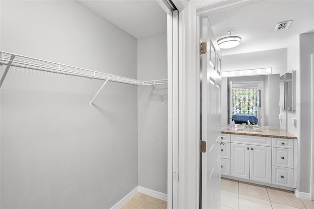 walk in closet with light tile patterned floors, visible vents, and a sink