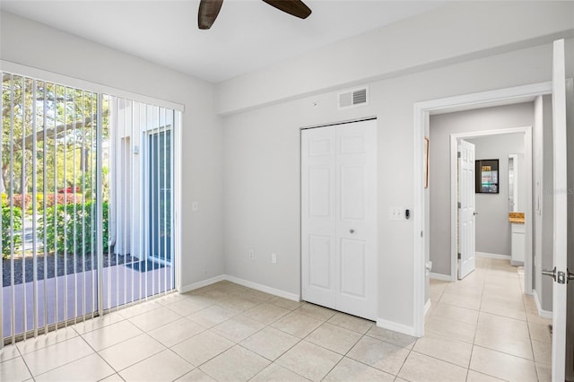 unfurnished bedroom featuring visible vents, baseboards, light tile patterned floors, a closet, and a ceiling fan