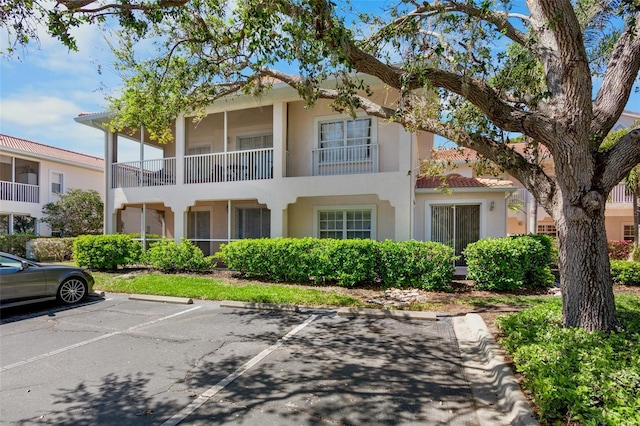 view of front of house with a tiled roof, uncovered parking, and stucco siding