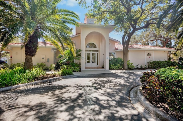 mediterranean / spanish-style home featuring stucco siding, french doors, and a tile roof