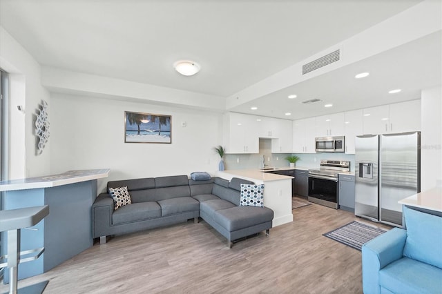 living room with recessed lighting, visible vents, and light wood-style floors