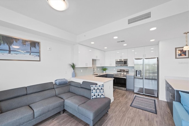 living room with recessed lighting, visible vents, and light wood finished floors