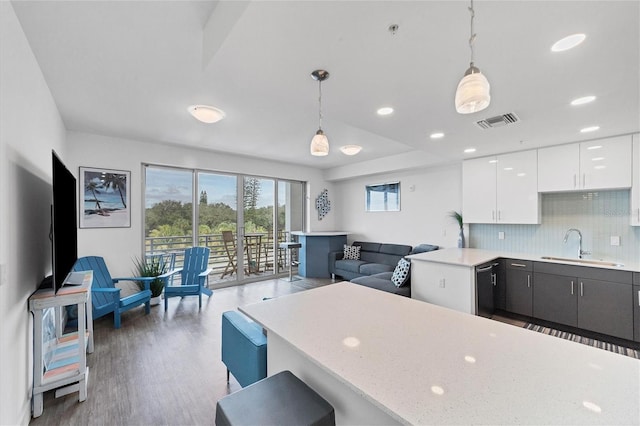 kitchen featuring visible vents, decorative backsplash, white cabinets, pendant lighting, and a sink