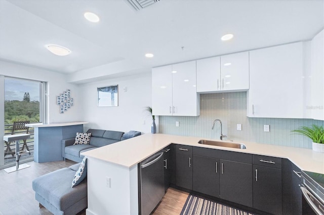 kitchen with stainless steel appliances, light countertops, a sink, and a peninsula