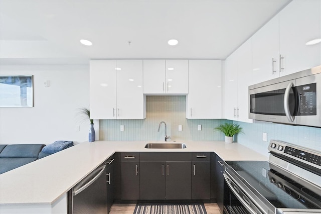 kitchen featuring tasteful backsplash, light countertops, appliances with stainless steel finishes, white cabinetry, and a sink