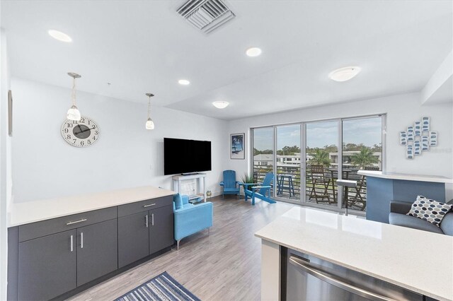 kitchen with visible vents, open floor plan, decorative light fixtures, light countertops, and light wood-type flooring