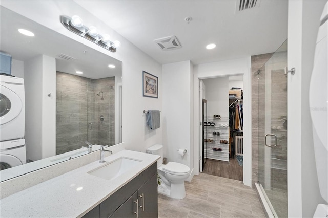 full bathroom featuring stacked washer and dryer, a shower stall, and visible vents