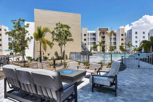 view of patio featuring a fire pit, fence, and a community pool