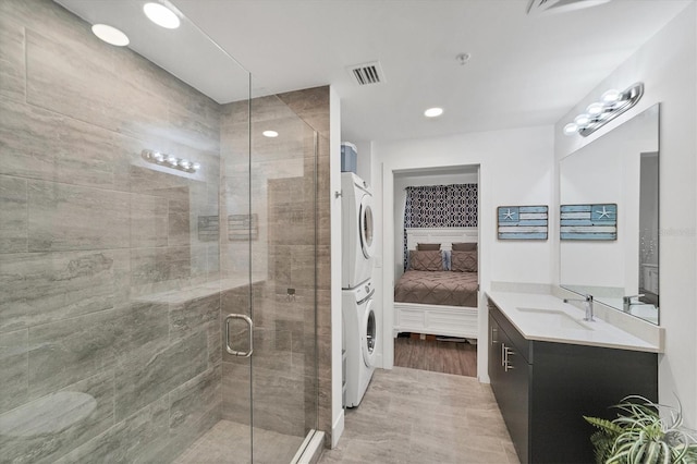 bathroom featuring visible vents, stacked washer and clothes dryer, ensuite bath, vanity, and a shower stall