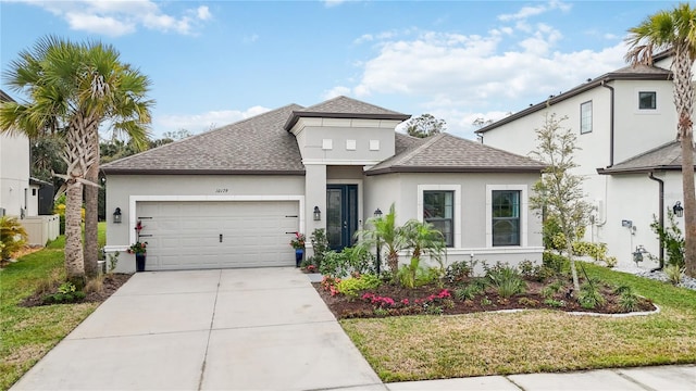 view of front facade with an attached garage, driveway, roof with shingles, stucco siding, and a front yard