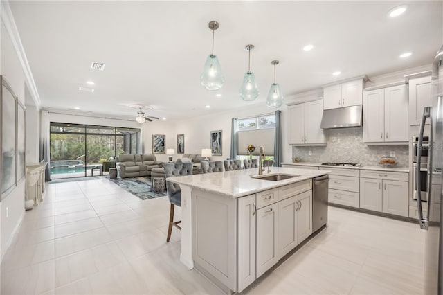 kitchen with under cabinet range hood, gas stovetop, a sink, visible vents, and decorative backsplash