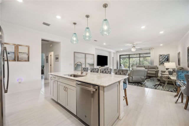 kitchen featuring stainless steel appliances, a sink, visible vents, open floor plan, and light stone countertops