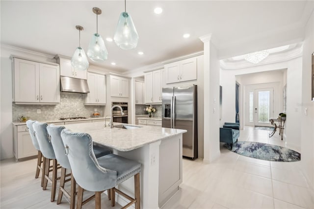 kitchen featuring appliances with stainless steel finishes, ornamental molding, a sink, under cabinet range hood, and backsplash