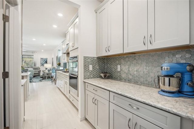 kitchen with light stone countertops, recessed lighting, decorative backsplash, and open floor plan