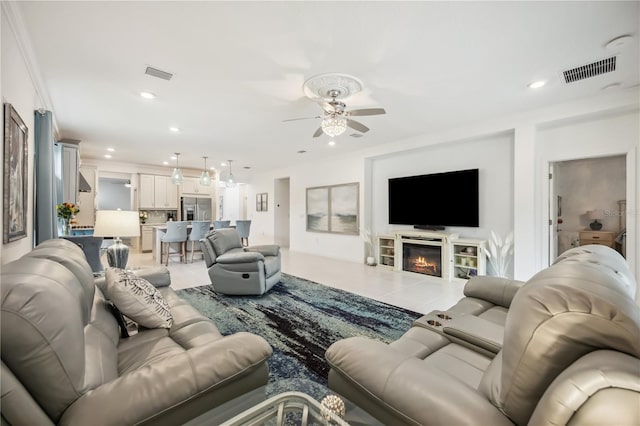 living area with a glass covered fireplace, visible vents, ceiling fan, and recessed lighting