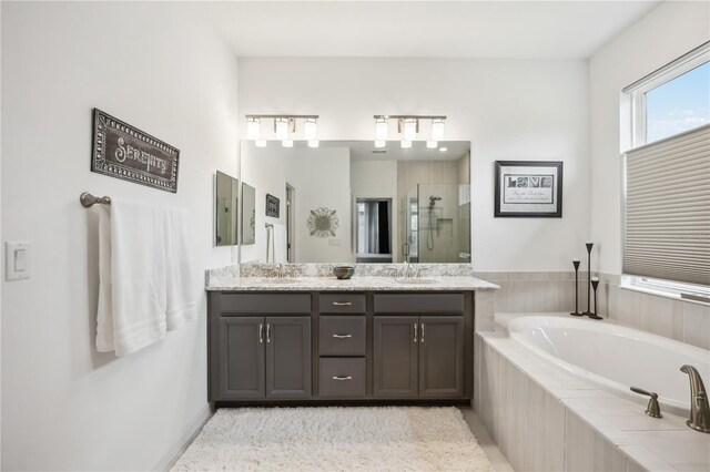 bathroom featuring a garden tub, a sink, a shower stall, and double vanity