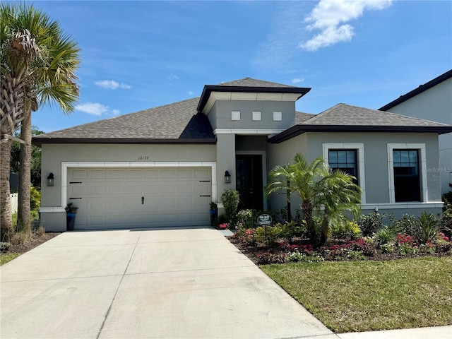 10179 Milky Way Cir, Sarasota, FL 34241 - prairie-style home featuring a shingled roof, a front lawn, a garage, stucco siding, and concrete driveway