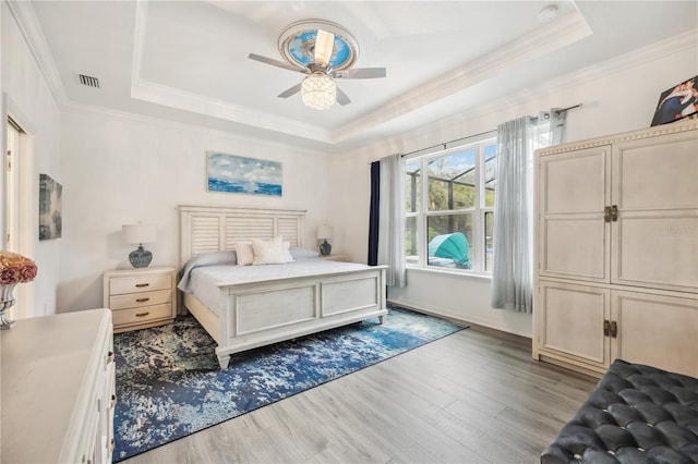 10179 Milky Way Cir, Sarasota, FL 34241 - bedroom with visible vents, ornamental molding, wood finished floors, a tray ceiling, and a ceiling fan
