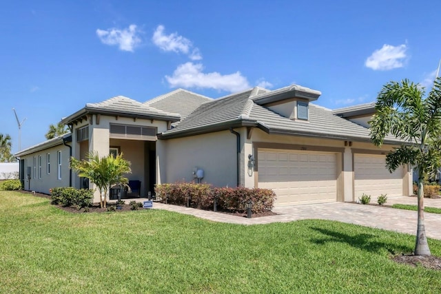 prairie-style house with a garage, decorative driveway, a front lawn, and stucco siding