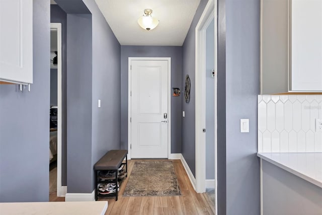 doorway featuring light wood-style flooring and baseboards