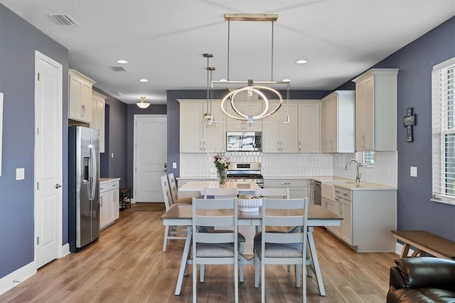 kitchen with visible vents, light countertops, appliances with stainless steel finishes, backsplash, and a center island