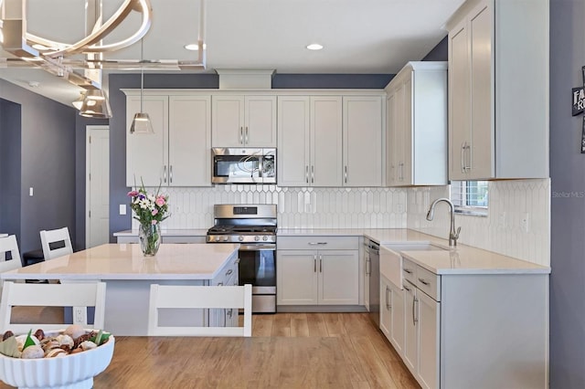 kitchen with a sink, backsplash, stainless steel appliances, and light countertops