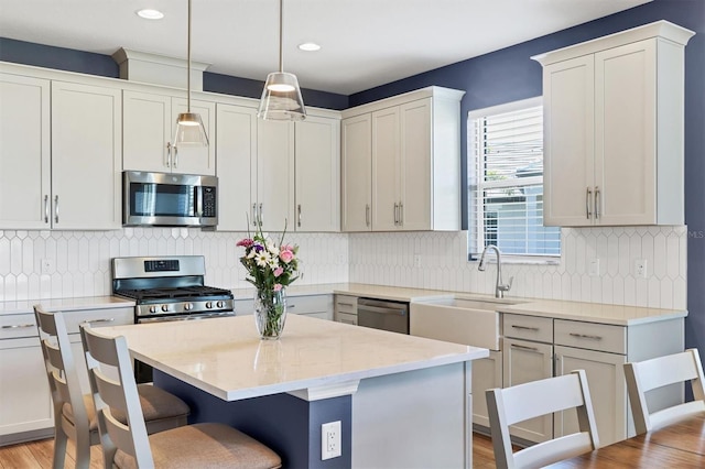 kitchen featuring a kitchen island, appliances with stainless steel finishes, a kitchen breakfast bar, pendant lighting, and a sink