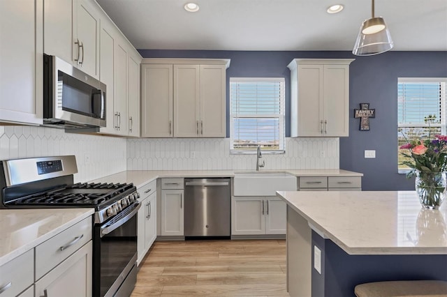 kitchen with plenty of natural light, appliances with stainless steel finishes, tasteful backsplash, and a sink