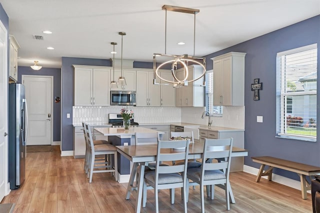 kitchen featuring tasteful backsplash, light countertops, visible vents, appliances with stainless steel finishes, and light wood-type flooring