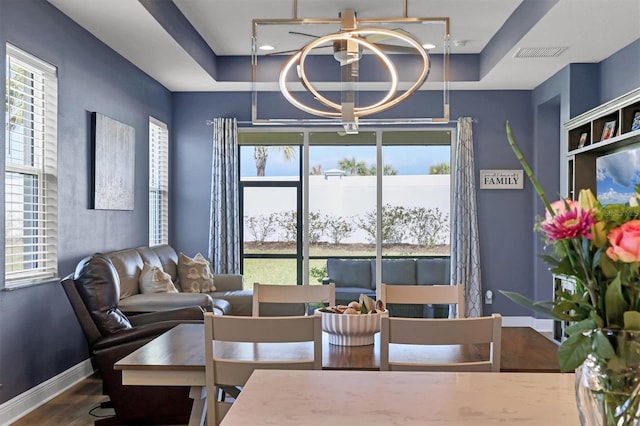 dining space featuring a healthy amount of sunlight, visible vents, a chandelier, and a raised ceiling