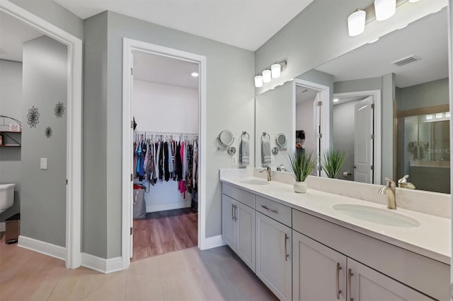 full bathroom with double vanity, a sink, visible vents, and baseboards