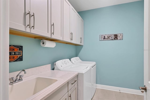 laundry room featuring cabinet space, baseboards, a sink, and washing machine and clothes dryer