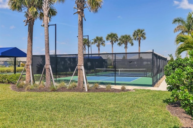 view of tennis court with fence and a yard