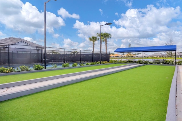 view of property's community with a tennis court and fence